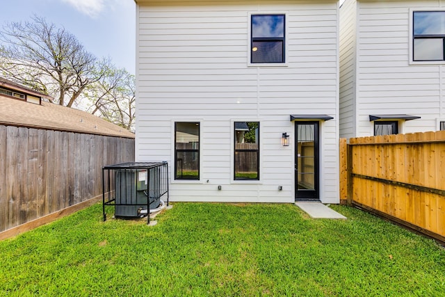 back of property featuring a lawn, central AC, and a fenced backyard