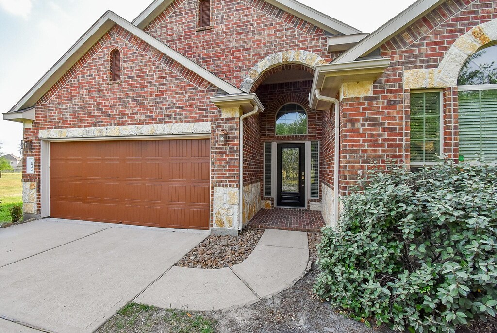 18942 W Windhaven Terrace Trl, Cypress, TX 77433 - exterior space featuring driveway, stone siding, an attached garage, and brick siding