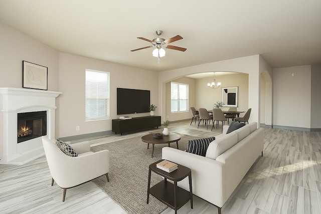 18942 W Windhaven Terrace Trl, Cypress, TX 77433 - living area featuring a glass covered fireplace, light wood finished floors, ceiling fan with notable chandelier, and arched walkways