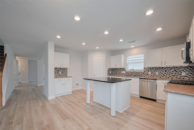kitchen with white cabinets, a kitchen island, decorative backsplash, and stainless steel appliances