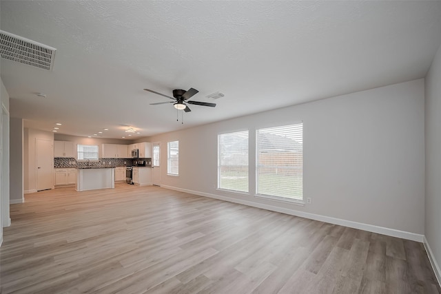 unfurnished living room featuring baseboards, a ceiling fan, and visible vents