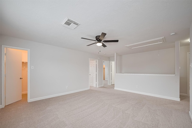 unfurnished room featuring visible vents, a ceiling fan, baseboards, attic access, and carpet flooring