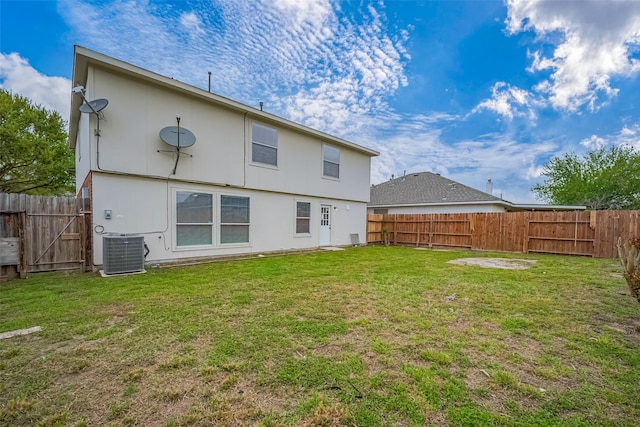 rear view of house with a yard, central AC, and a fenced backyard