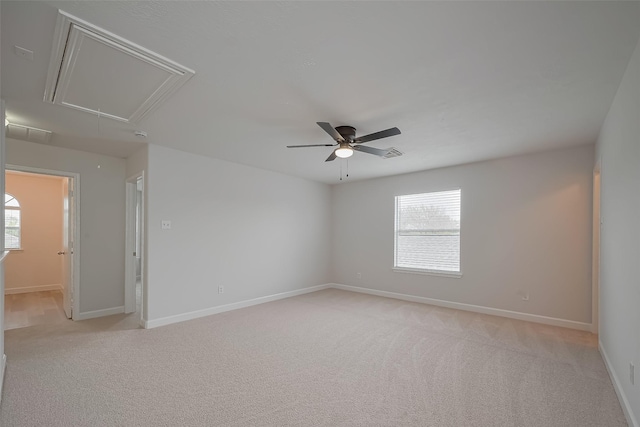 unfurnished room with attic access, baseboards, light colored carpet, and ceiling fan