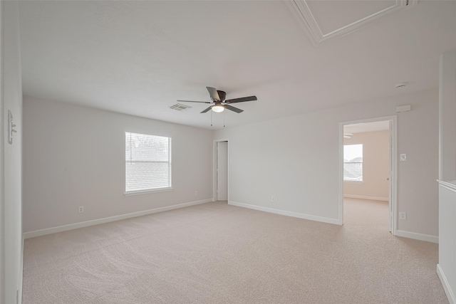 unfurnished room featuring a ceiling fan, attic access, light carpet, baseboards, and visible vents