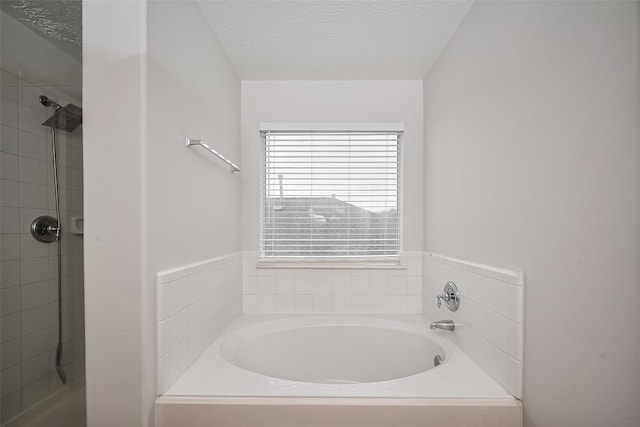 full bathroom featuring a bath, a textured ceiling, and tiled shower