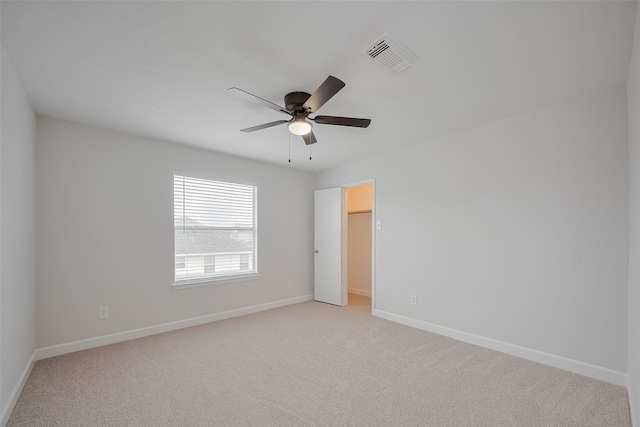 unfurnished bedroom with a spacious closet, light carpet, visible vents, and baseboards