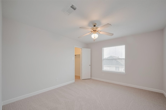 spare room featuring ceiling fan, baseboards, visible vents, and light carpet