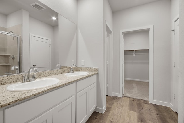 16899 Needlepoint Dr, Conroe, TX 77302 - full bathroom with double vanity, a stall shower, wood finished floors, and a spacious closet