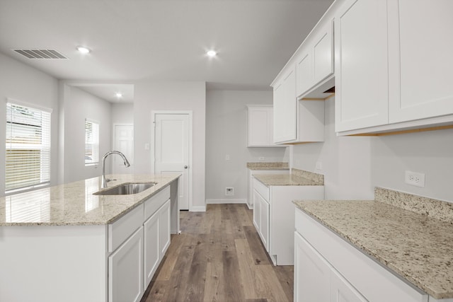 16899 Needlepoint Dr, Conroe, TX 77302 - kitchen featuring light wood-style flooring, a kitchen island with sink, white cabinets, light stone counters, and recessed lighting