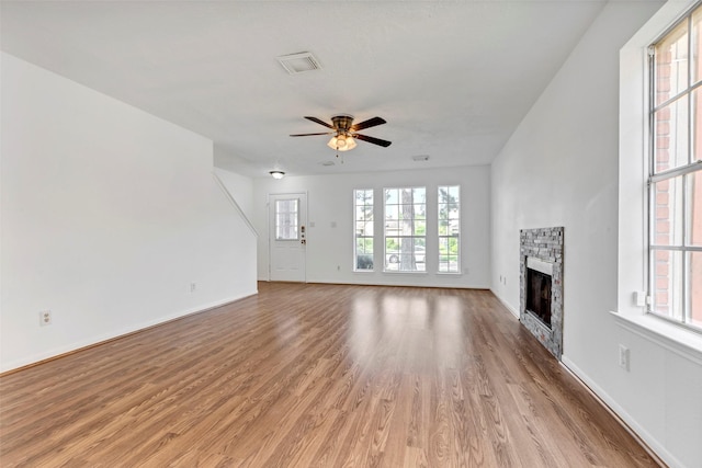 unfurnished living room featuring light wood finished floors, visible vents, baseboards, a fireplace, and ceiling fan