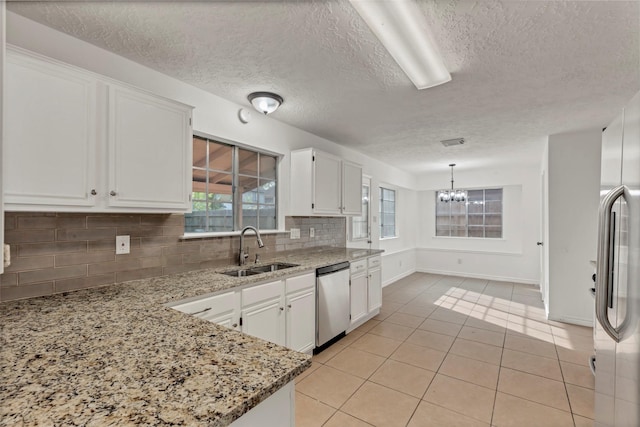 kitchen featuring a sink, decorative backsplash, a chandelier, white cabinetry, and appliances with stainless steel finishes