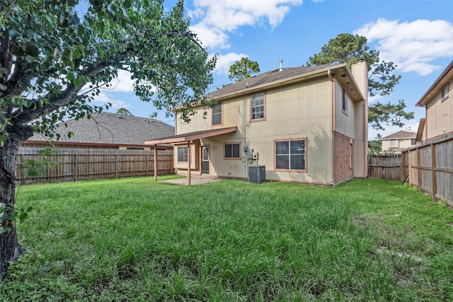 rear view of house featuring cooling unit, a lawn, a fenced backyard, and a chimney