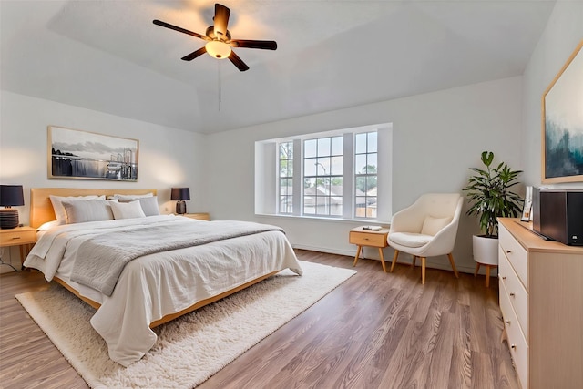bedroom featuring wood finished floors, lofted ceiling, and a ceiling fan