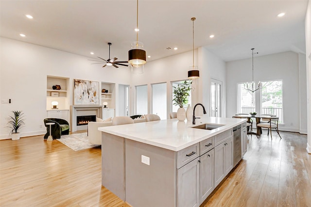 kitchen with recessed lighting, a sink, an island with sink, and a lit fireplace