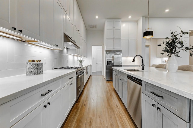 kitchen with tasteful backsplash, a sink, light wood finished floors, appliances with stainless steel finishes, and visible vents