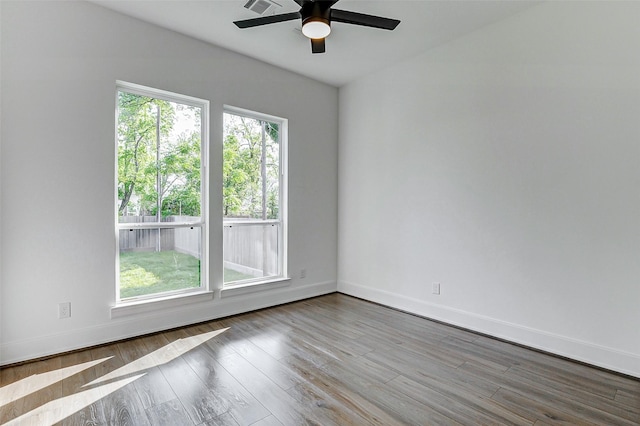 empty room featuring ceiling fan, baseboards, wood finished floors, and visible vents