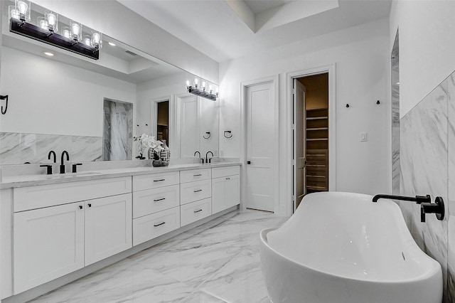 bathroom featuring a tray ceiling, a sink, and double vanity