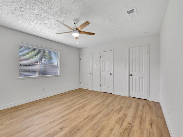 403 Elder Vista Dr, Houston, TX 77598 - unfurnished bedroom with a textured ceiling, multiple closets, light wood-type flooring, baseboards, and visible vents