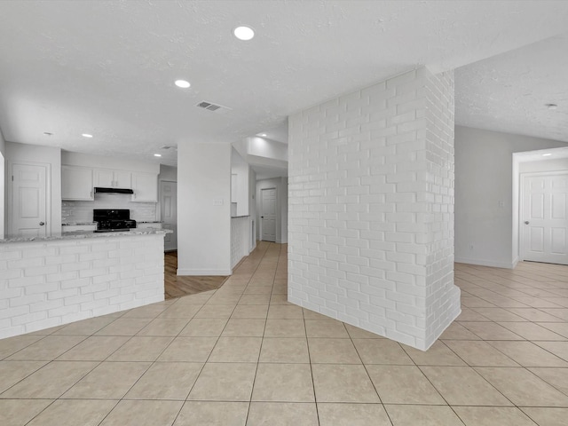 403 Elder Vista Dr, Houston, TX 77598 - kitchen with visible vents, light tile patterned floors, gas stove, a textured ceiling, and white cabinetry
