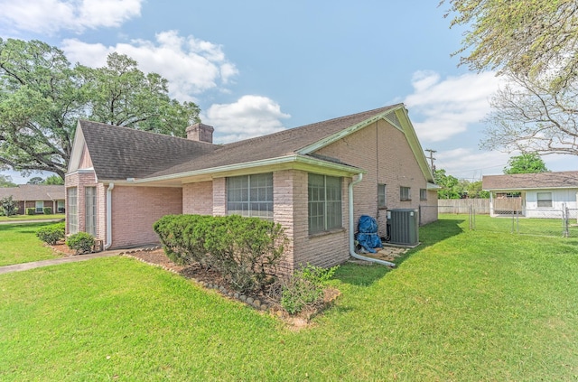1345 10th St, Hempstead, TX 77445 - view of property exterior with central AC, a chimney, fence, a yard, and brick siding