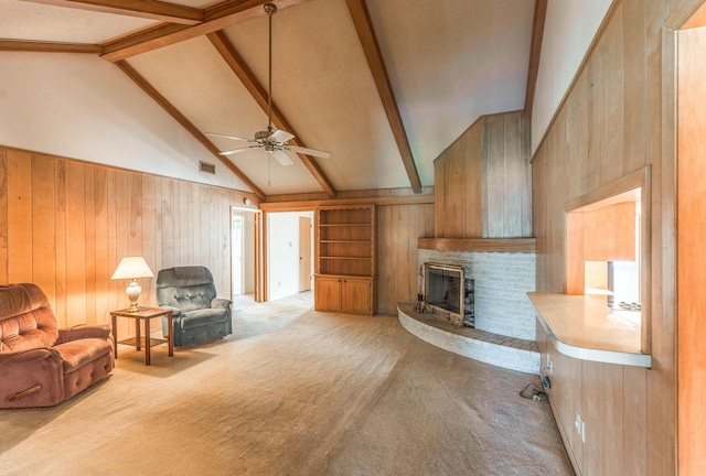 1345 10th St, Hempstead, TX 77445 - living room featuring lofted ceiling with beams, wooden walls, ceiling fan, a fireplace, and light colored carpet