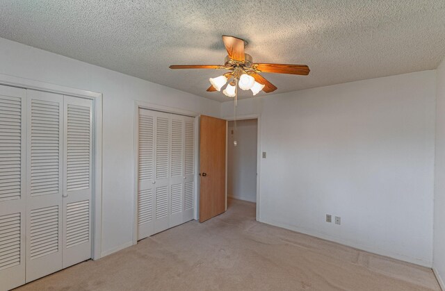 1345 10th St, Hempstead, TX 77445 - unfurnished bedroom featuring carpet, multiple closets, a ceiling fan, baseboards, and a textured ceiling