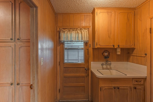 1345 10th St, Hempstead, TX 77445 - interior space with a sink, a textured ceiling, wood walls, light countertops, and ornamental molding