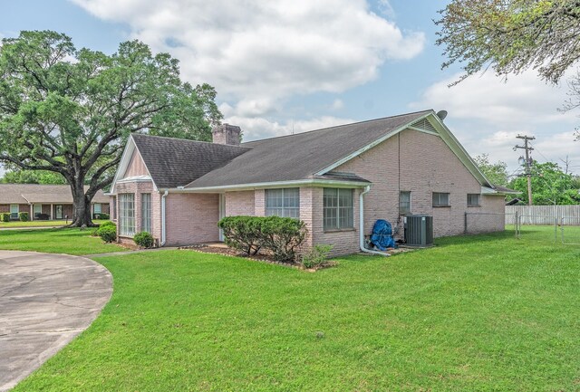 1345 10th St, Hempstead, TX 77445 - view of side of home featuring a chimney, fence, a yard, central air condition unit, and brick siding