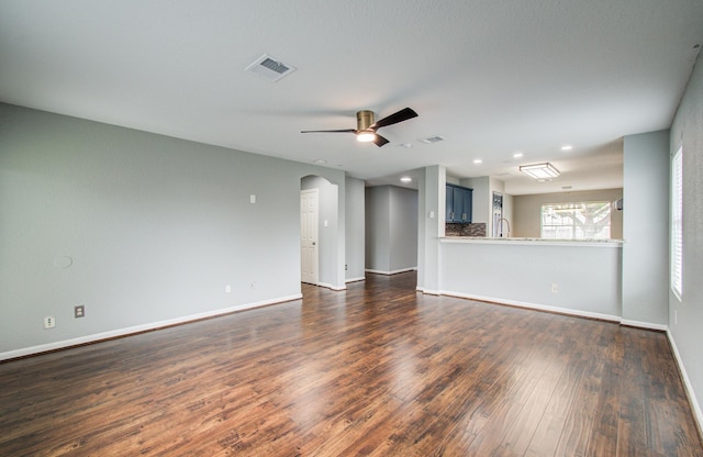5823 Plantation Crest Dr, Katy, TX 77449 - unfurnished living room with arched walkways, dark wood finished floors, baseboards, visible vents, and a ceiling fan