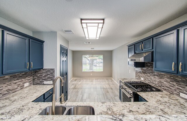 5823 Plantation Crest Dr, Katy, TX 77449 - kitchen featuring gas range, blue cabinetry, range hood, and a sink