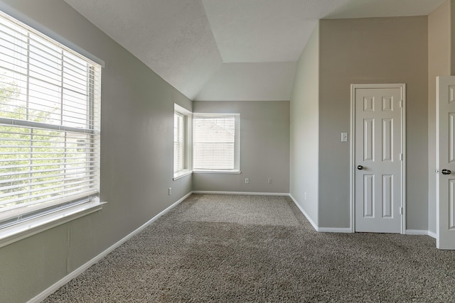 unfurnished room featuring lofted ceiling, carpet flooring, and baseboards
