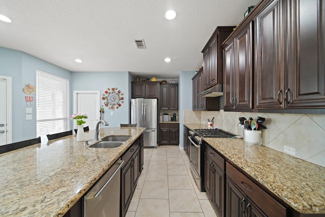 kitchen with stainless steel appliances, a sink, tasteful backsplash, visible vents, and under cabinet range hood