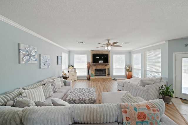 living area featuring light wood finished floors, a ceiling fan, a textured ceiling, and ornamental molding