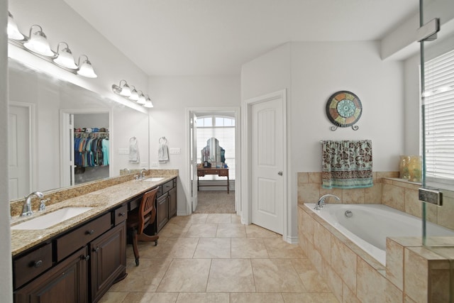 bathroom with double vanity, a bath, tile patterned floors, and a sink