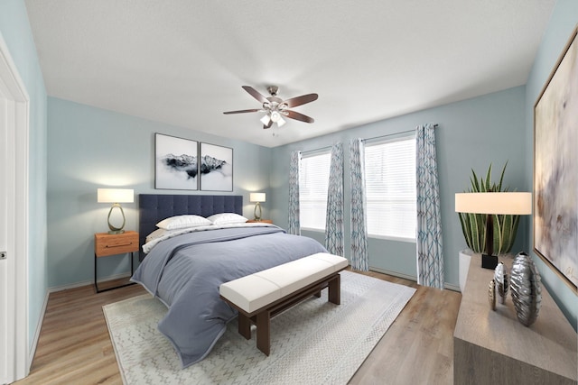 bedroom with light wood-style flooring, baseboards, and ceiling fan