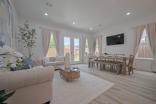 living area with recessed lighting, visible vents, light wood finished floors, and french doors