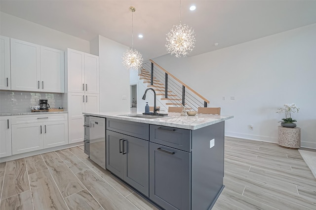 kitchen with white cabinets, a sink, a notable chandelier, and gray cabinets