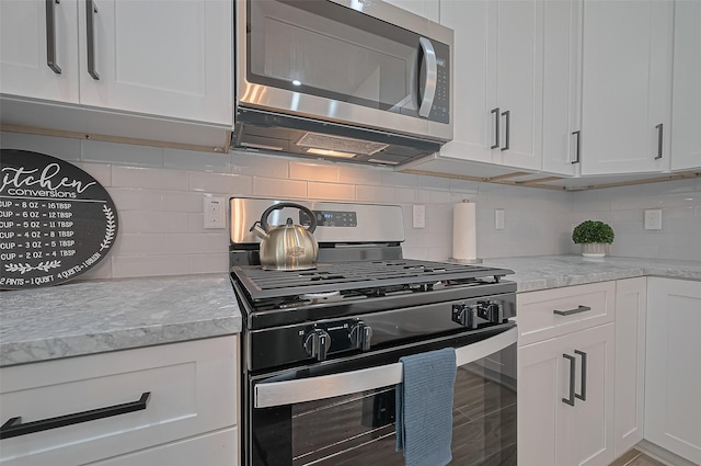 kitchen featuring decorative backsplash, appliances with stainless steel finishes, and white cabinetry