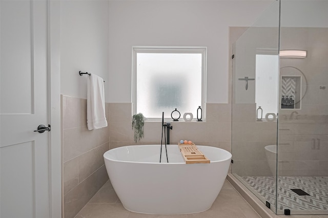 full bath featuring a freestanding bath, a shower stall, tile walls, and tile patterned floors