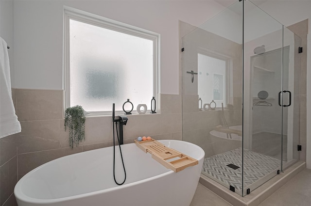 full bathroom featuring a shower stall, a freestanding tub, tile walls, and wainscoting