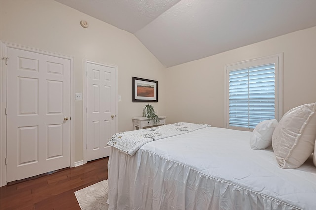 bedroom with dark wood-style flooring and vaulted ceiling
