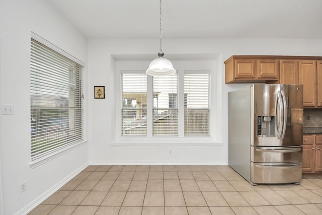 kitchen featuring plenty of natural light, pendant lighting, stainless steel fridge, and dark countertops