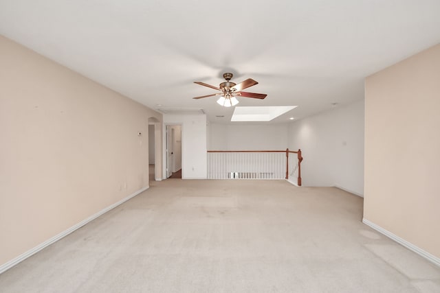 unfurnished room with attic access, ceiling fan, light carpet, and a skylight