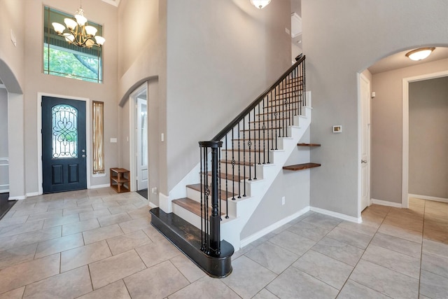 tiled entryway featuring a towering ceiling, arched walkways, and a chandelier