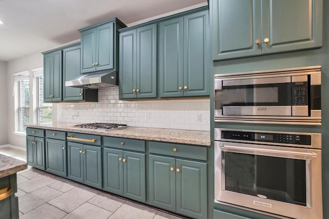 kitchen featuring stainless steel appliances, under cabinet range hood, decorative backsplash, and light tile patterned floors