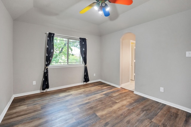empty room featuring arched walkways, baseboards, lofted ceiling, wood finished floors, and ceiling fan