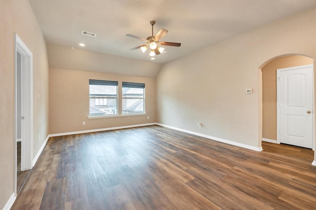 spare room featuring dark wood-style floors, arched walkways, visible vents, baseboards, and a ceiling fan