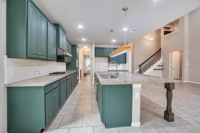 kitchen with arched walkways, visible vents, decorative backsplash, and a sink