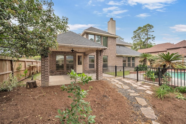 rear view of property with a fenced backyard, a shingled roof, ceiling fan, a patio, and brick siding